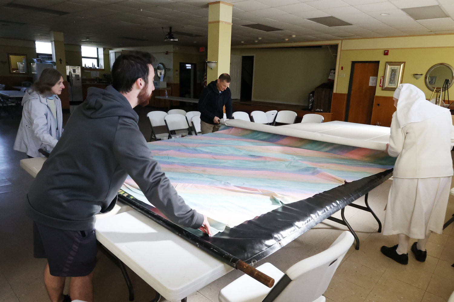 From left, Marie Magill, Jacob Losardo, Marc Auger and Sister Grace Coffee unpack on Saturday the 8-foot by 12-foot painted image of Divine Mercy so it can be displayed in a frame in the foyer of St. Theresa Church in advance of Divine Mercy Sunday, April 16.